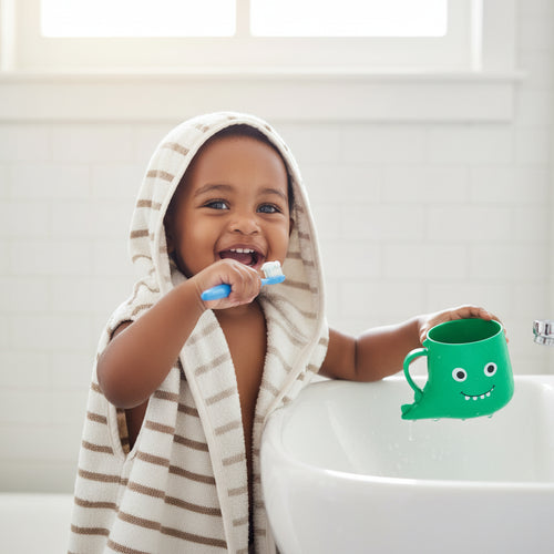 Green cup with a smiley face held by a child's hand on a white background
