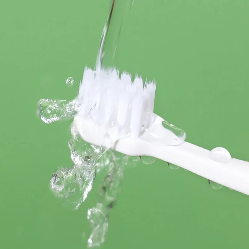 White toothbrush with toothpaste on a green background